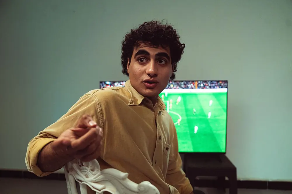 Torcedor reagindo a lance de futebol transmitido ao vivo em casa