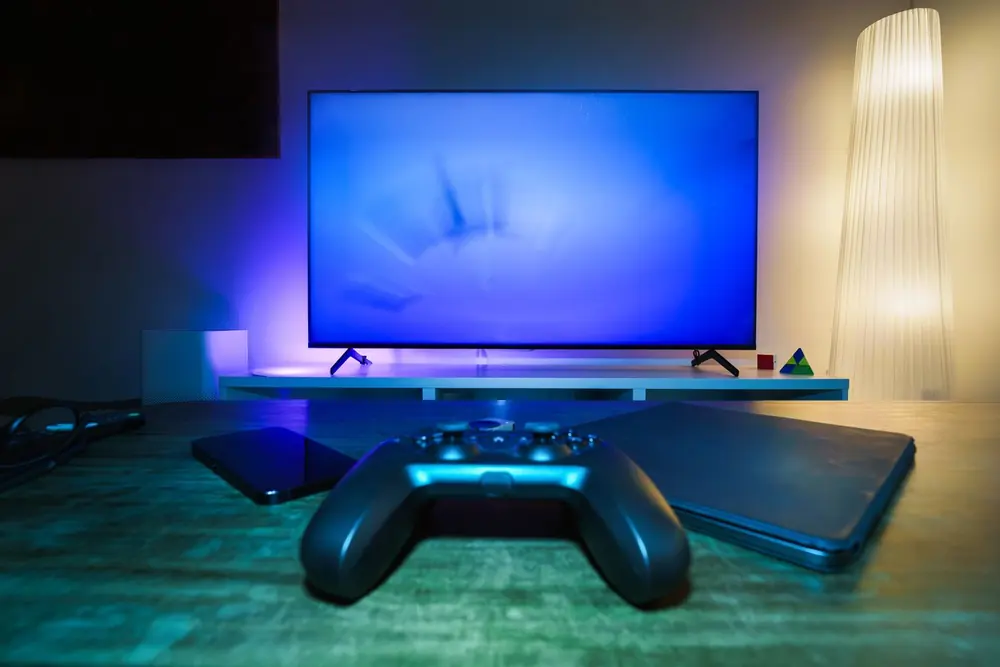 Aparelho de TV box e controle sobre móvel com televisor ao fundo